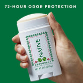 Hand holding a Native deodorant stick with a green background and text about odor protection.
